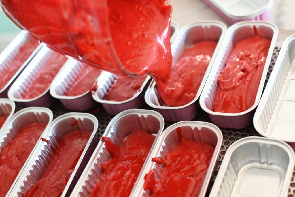 pouring red velvet cake into mini tins