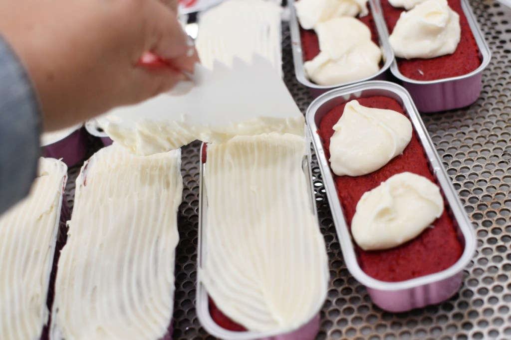 spreading cream cheese frosting on cakes in mini loaf tins