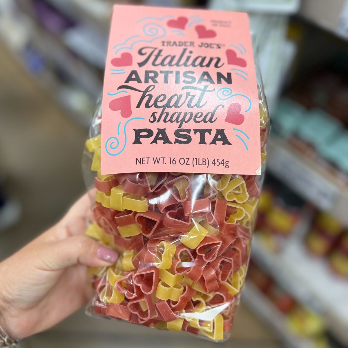 a womans hand holding a bag heart shaped pasta