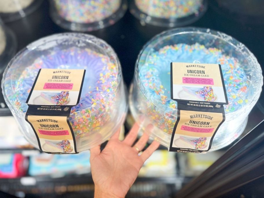 a womans hand holding two unicorn ice cream cakes