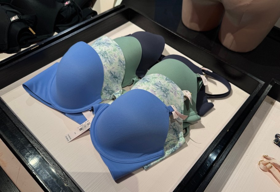 stack of blue and green victorias secret bras on store shelf