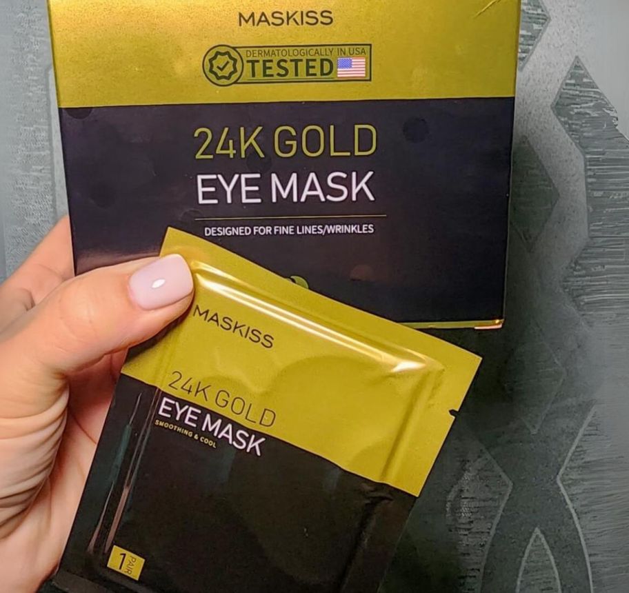 a hand holding a packet and a box of gold eye masks