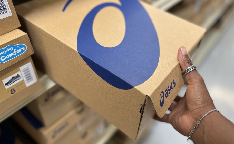 a womans hand grabbing a shoe box off a store shelf. 