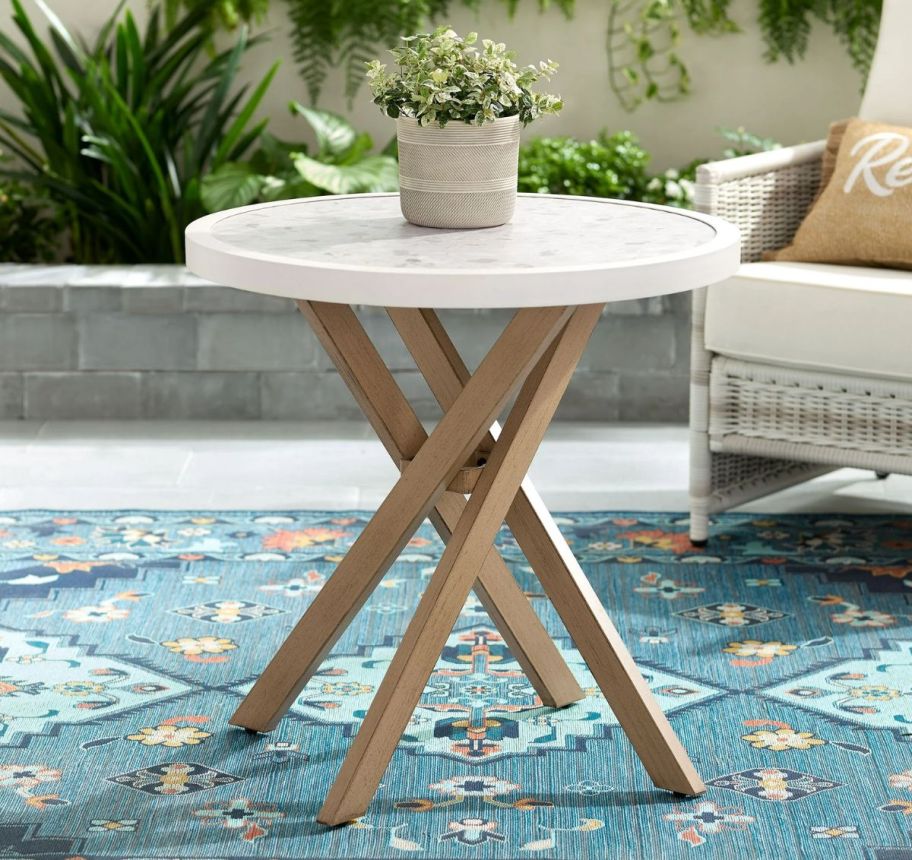 a white bistro table next to a chair sitting outside on a patio