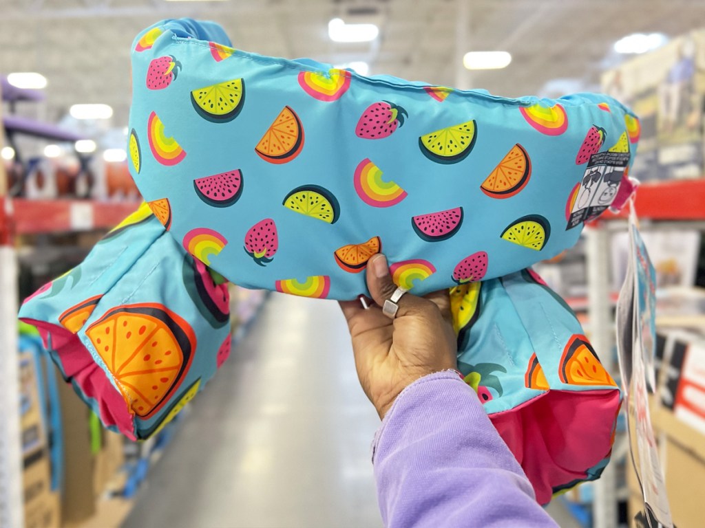 hand holding up a fruit print paddle pals kids life jacket