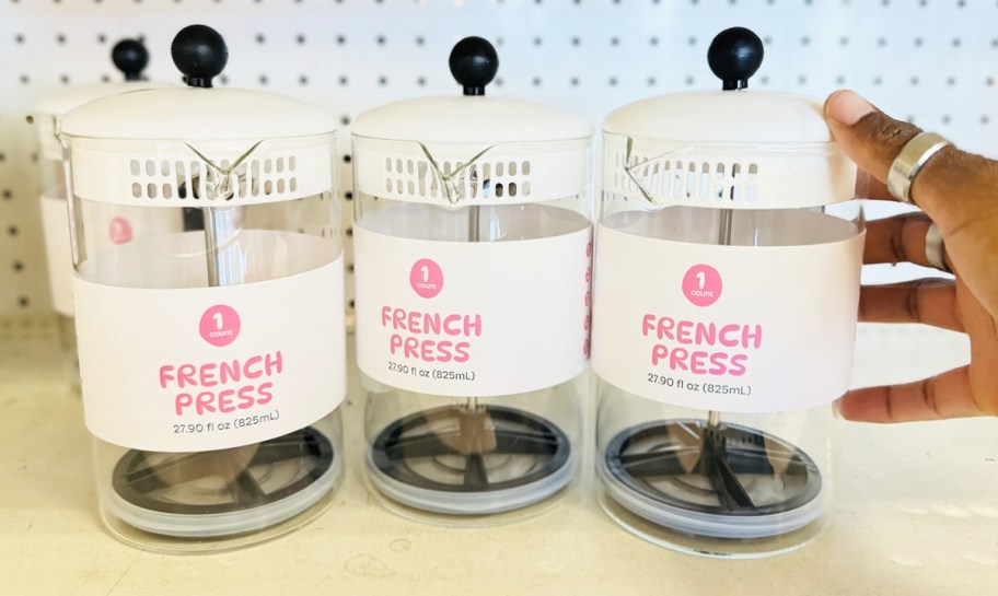 hand touching a row of french presses on store shelf