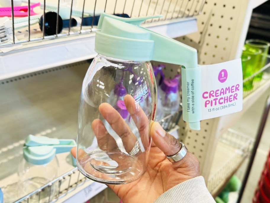 hand holding up a small glass creamer pitcher in store