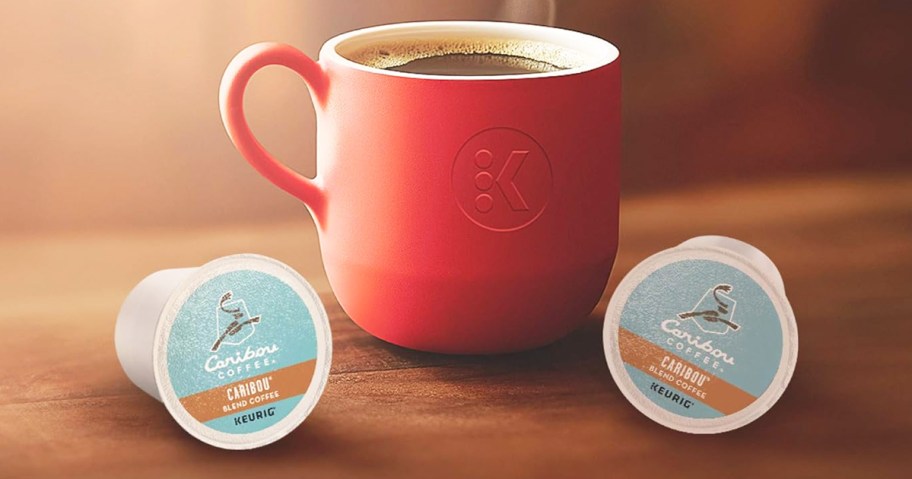 red coffee mug next to two Caribou Coffee K-Cups