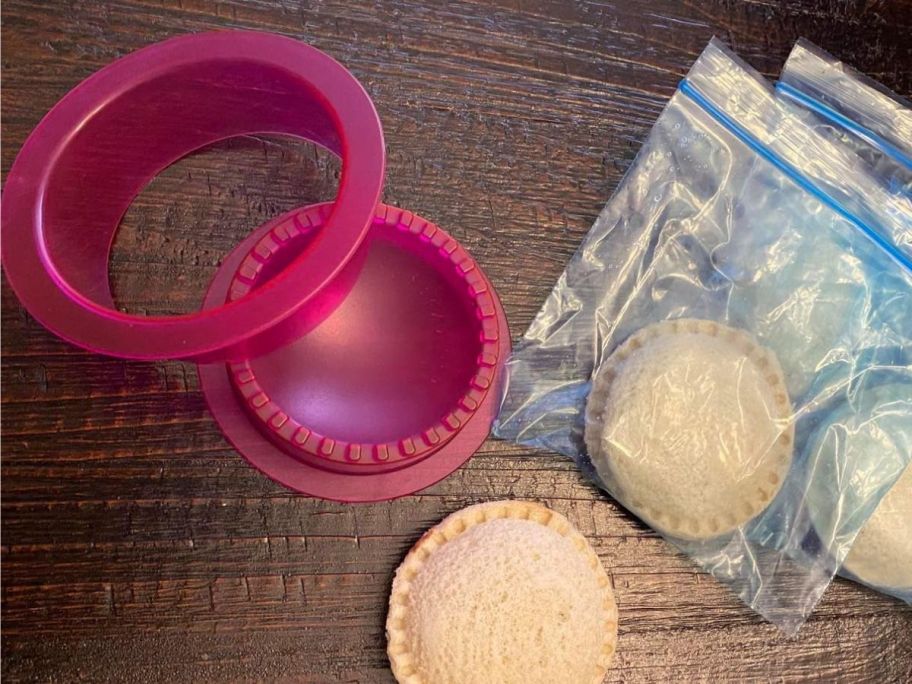 ADarsun Uncrustable Sandwich Cutter in Pink beside a few uncrustable sandwiches 