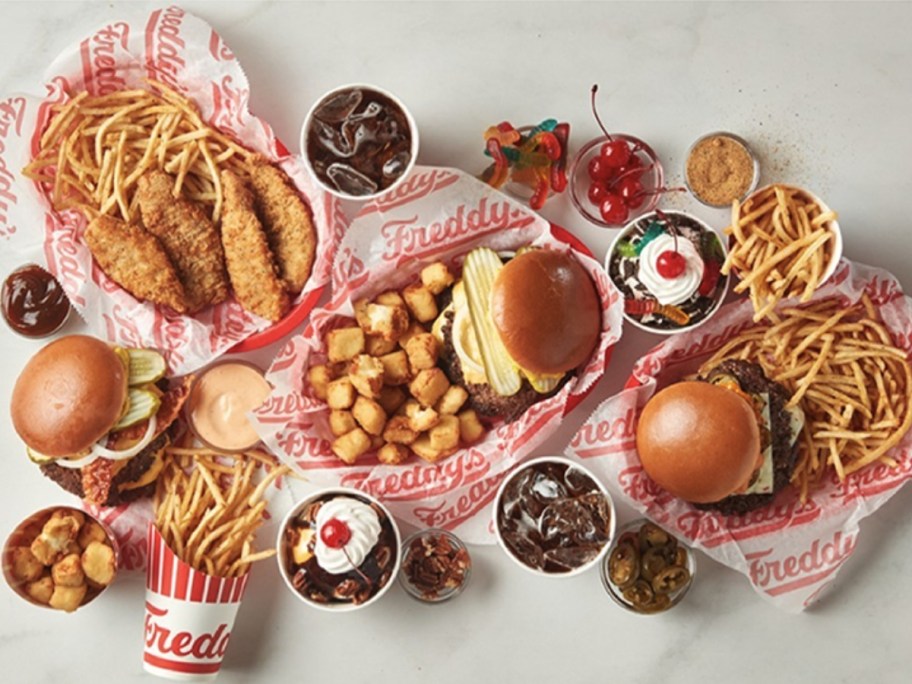 meal platters with burgers and fries, chicken sandwich and tots, chicken tenders and fries, ice cream sundaes, ice cream shakes, cups of soda from Freddy's restaurant