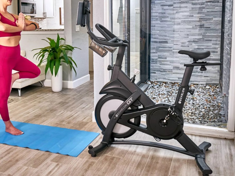 woman doing yoga in front of an indoor exercise bike