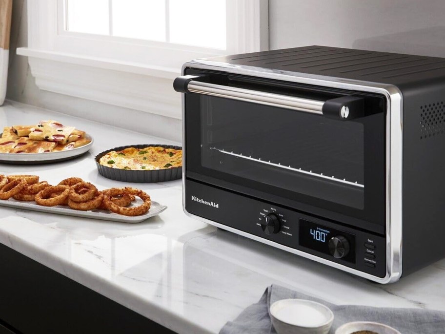 black and silver countertop oven on counter with plates of food