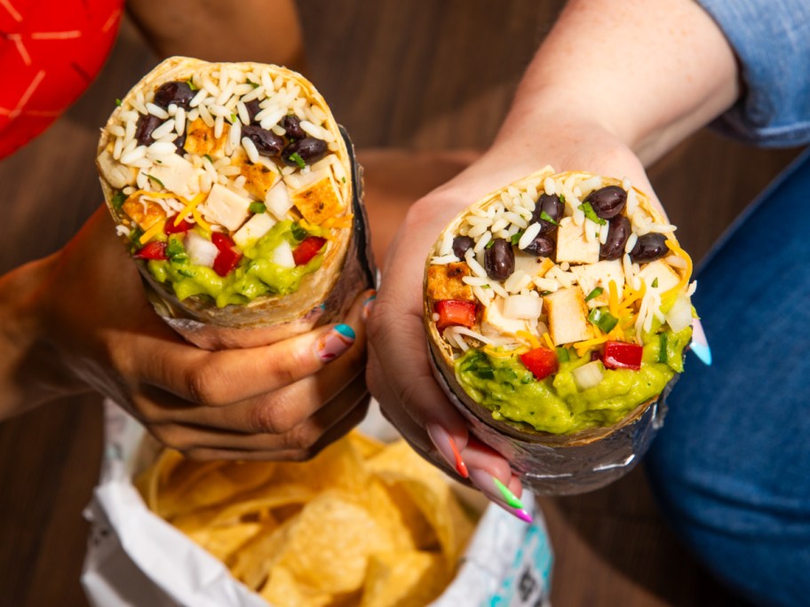 holding 2 burritos over a bag of chips