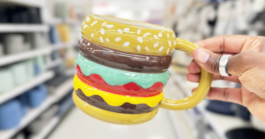 hand holding up a cheeseburger shaped coffee mug