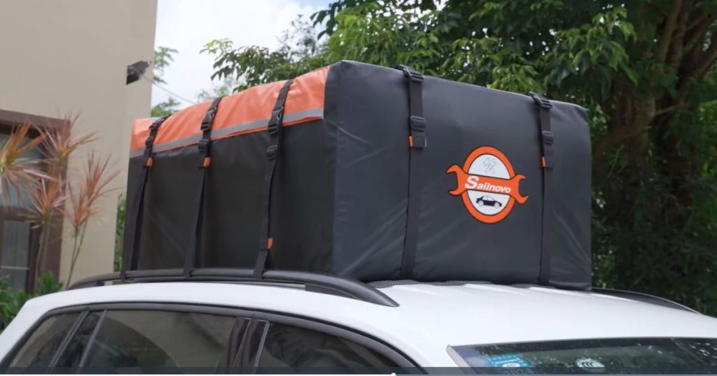 white car with a black and orange car rooftop carrier bag on top