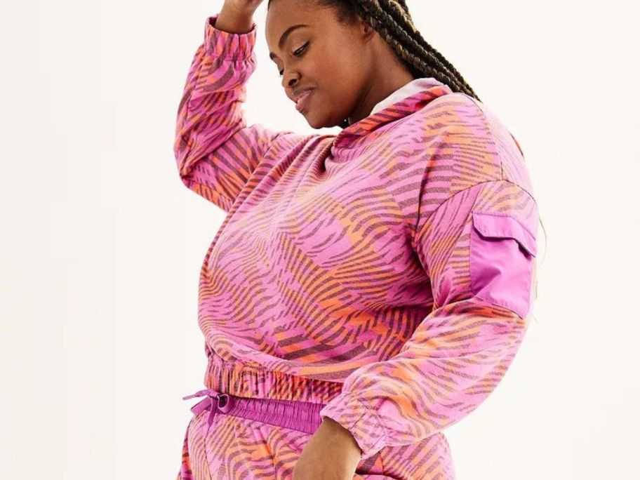 A woman wearing a pink patterned Tek Gear Plus Size Cargo Hoodie