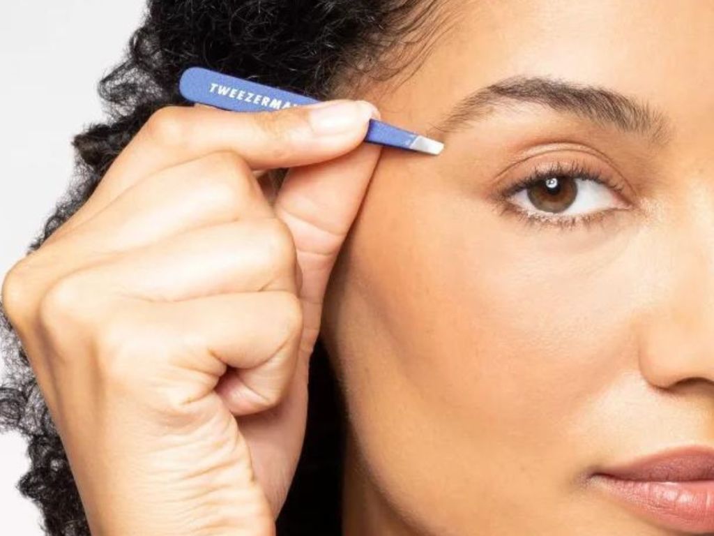 Woman using a pair of Tweezerman mini slant tweezers on her eyebrow