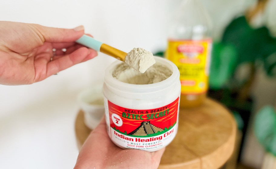 hand holding a container of aztec healing clay 