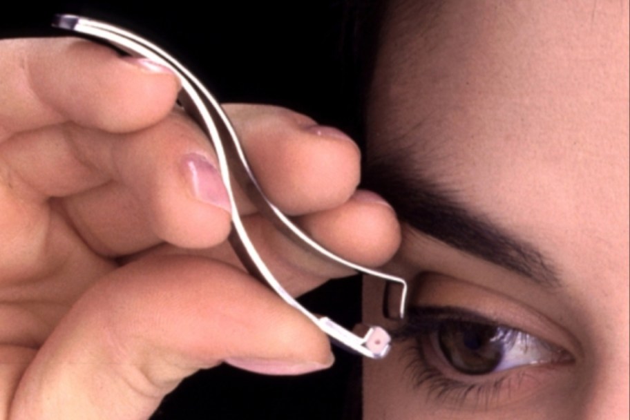 woman curling eyelashes with japanese eyelash curler