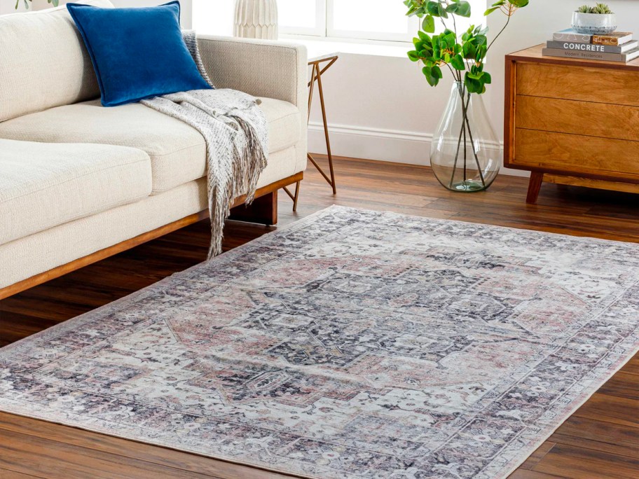 blue and gray rug with design on floor next to cream colored couch