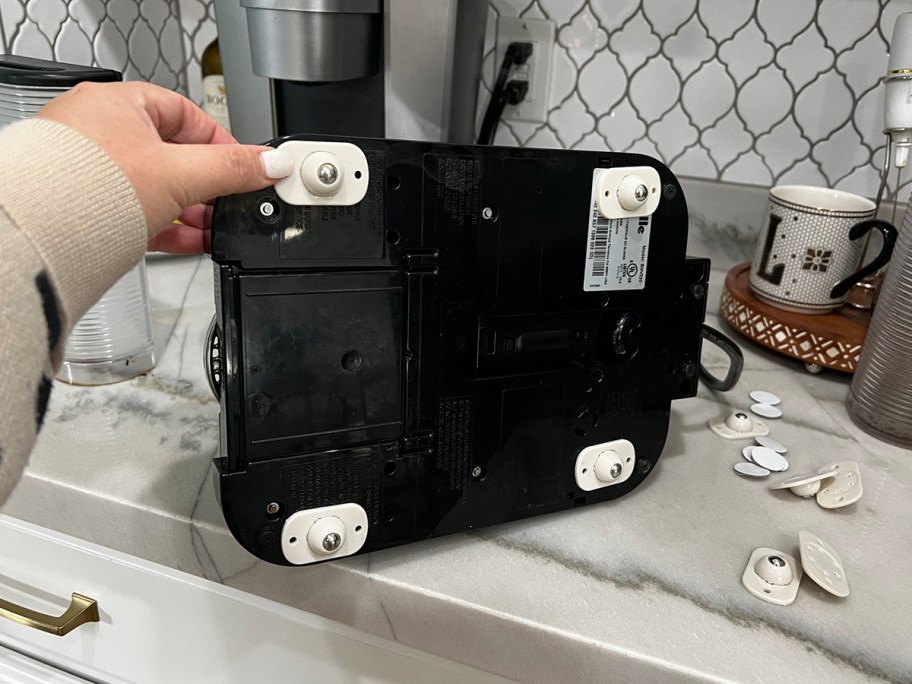 hand holding toaster on it's side with white caster wheels stuck to the bottom