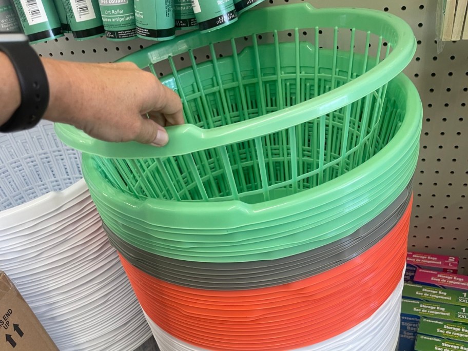 hand reaching for a large slotted laundry basket in green, more below in other colors