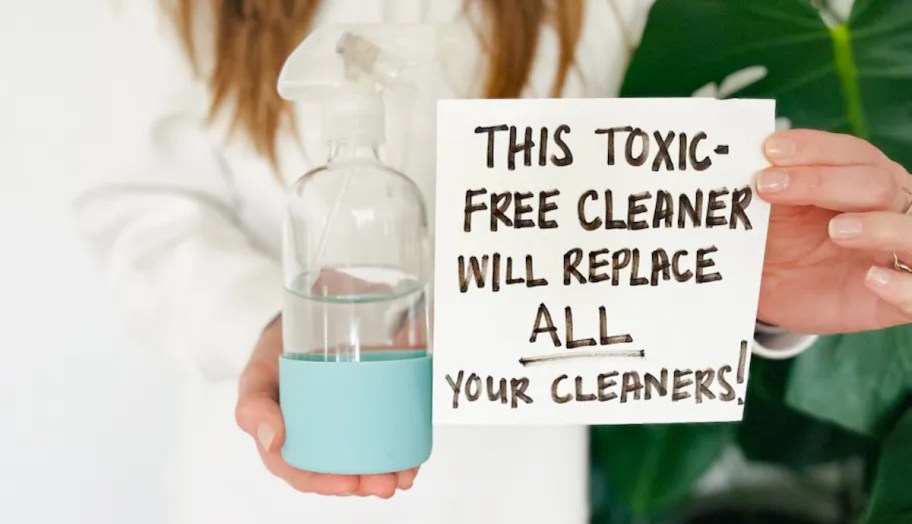 hand holding toxic free cleaner sign with bottle of clear cleaner