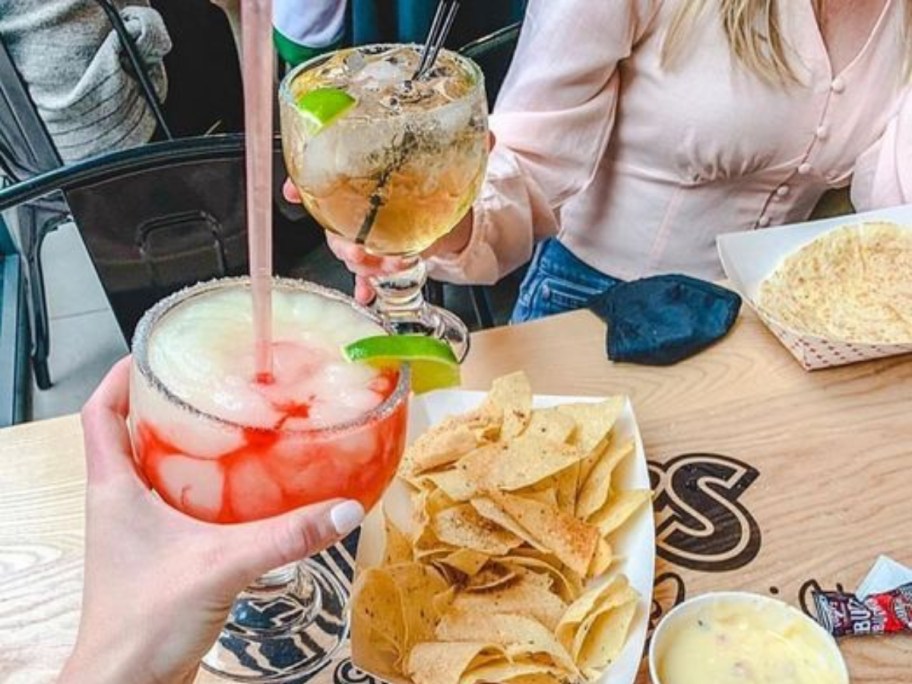 toasting with Margaritas over a plate of chips