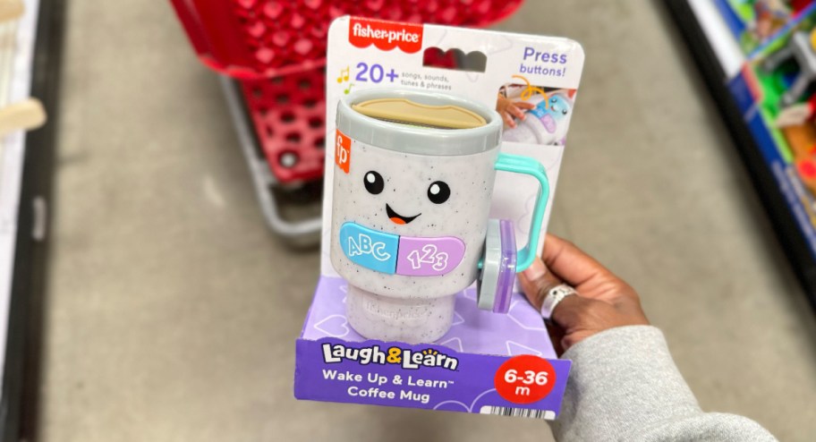 hand holding Fisher Price Coffee mug toy at the store in front of target cart