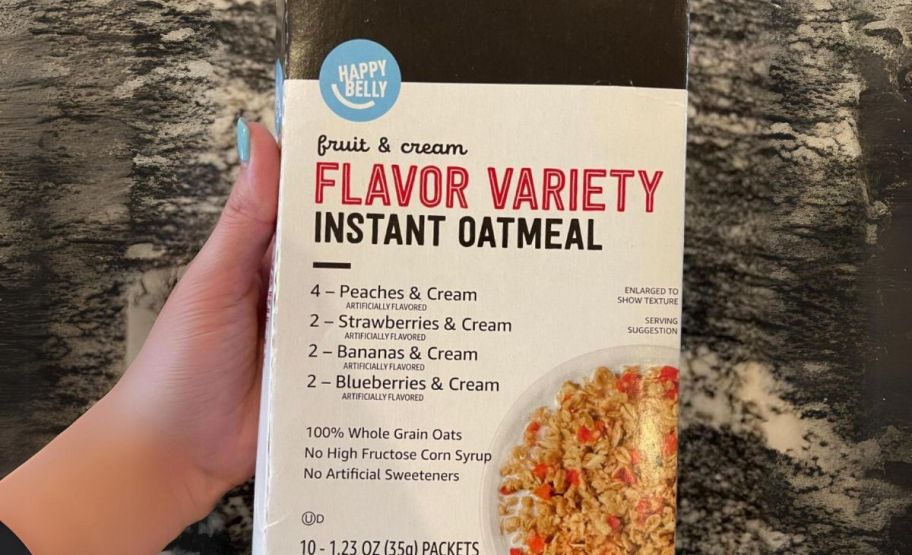 a womans hand holding a box of happy belly instant oatmeal