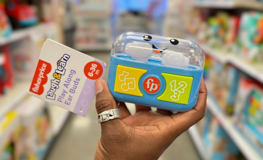 a womans hand holding a set of fisher-price play along laugh and learn ear buds