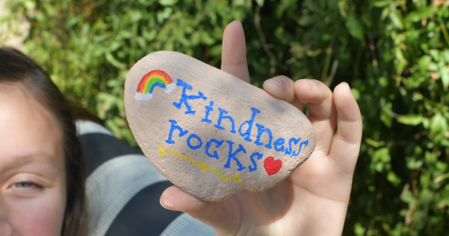 holding a rock with "kindness rocks" painted on it