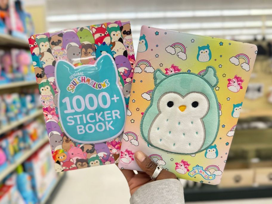 hand holding up a Squishmallows sticker book and activity journal with Squishmallow characters on them