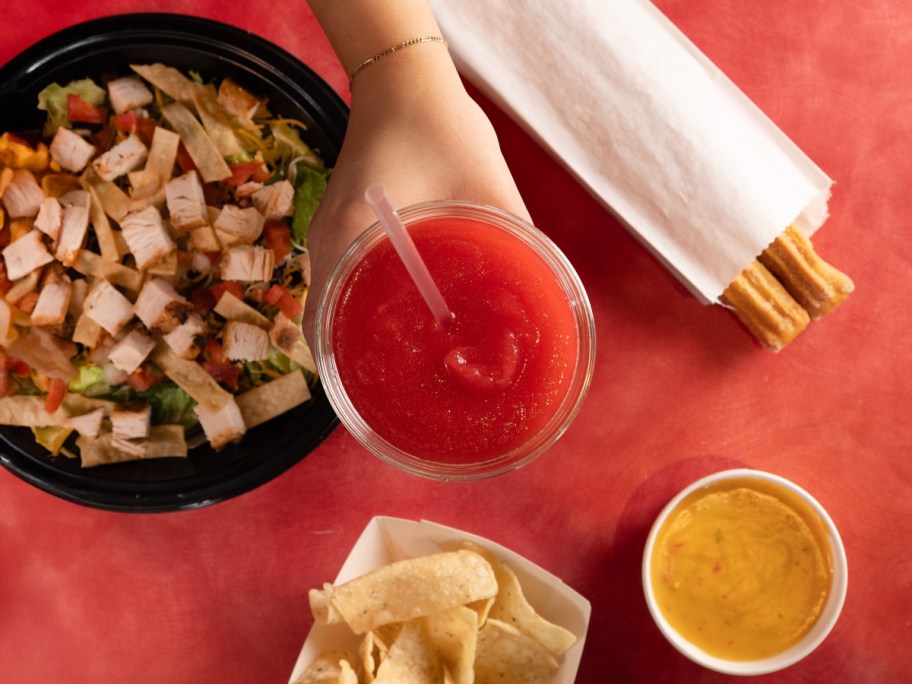 holding a red margarita near tex-mex food