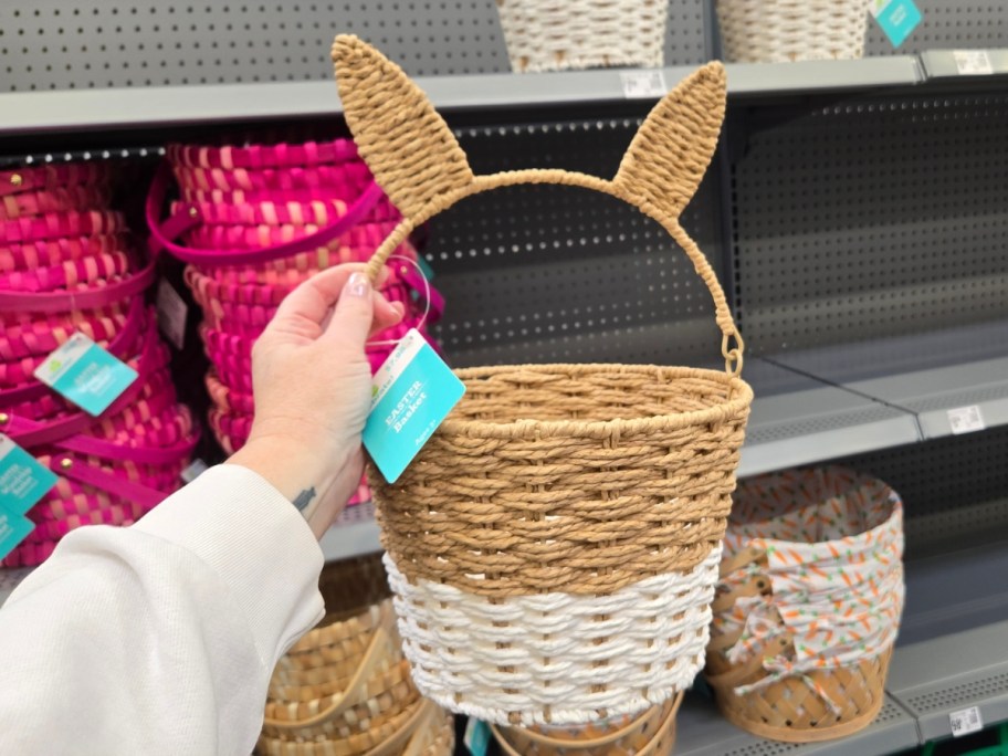 hand holding a natural brown and white easter basket with bunny ears in a store aisle