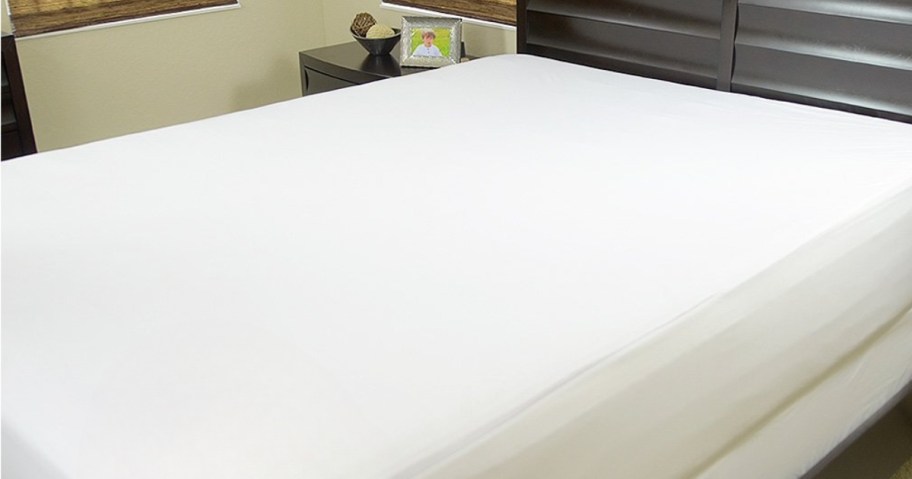 bed with a white mattress protector on it, wood headboard