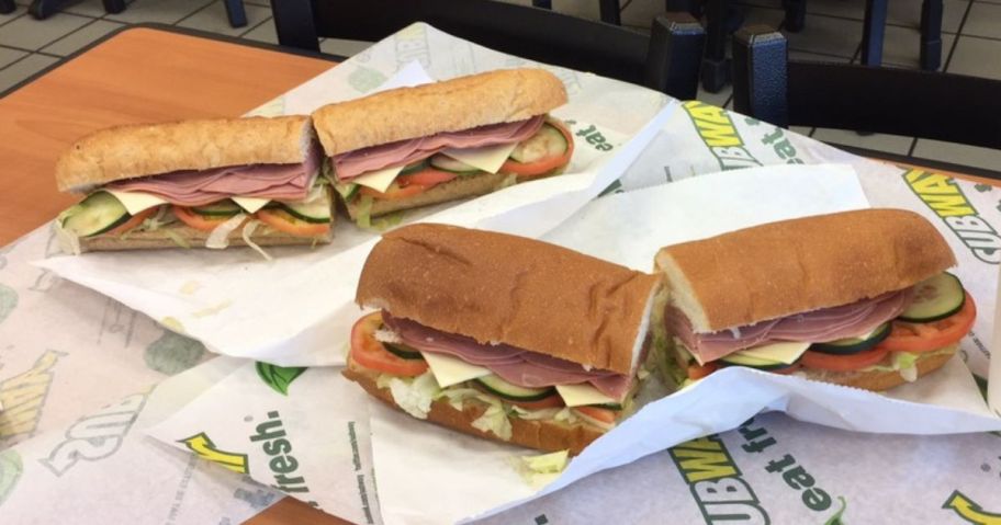 2 unwrapped subway subs on a dining table