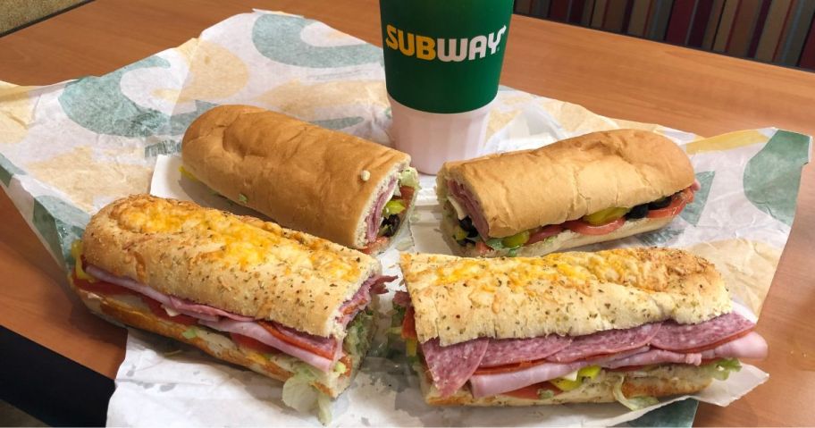 2 unwrapped subway subs and a fountain drink on a tabler