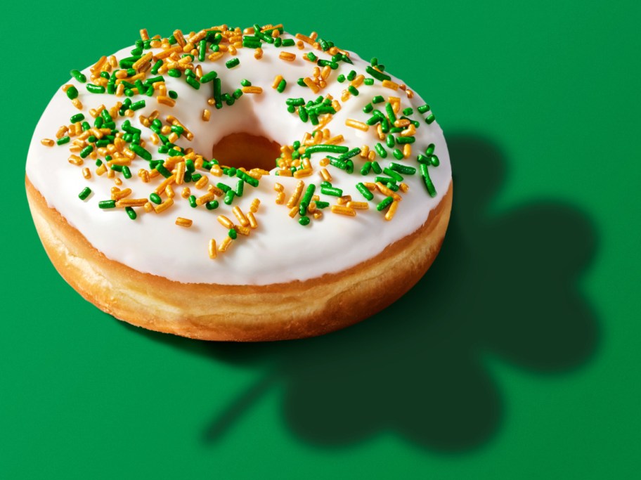 frosted doughnut casting a shamrock-shaped shadow on a green background
