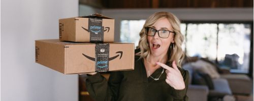 Collin holding Amazon boxes and pointing to them with her other hand