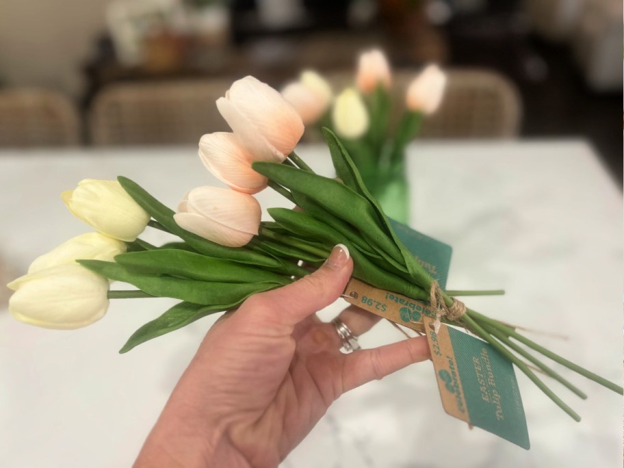 Person holding artificial bundles of pink and white tulips