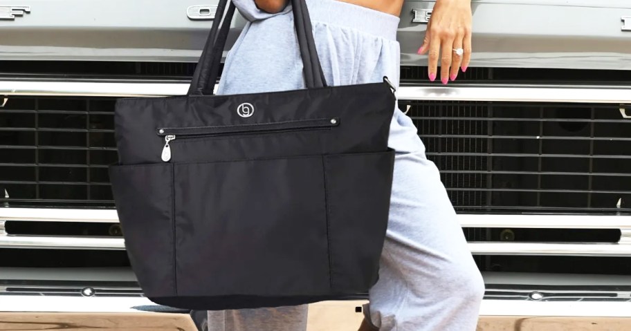 woman standing in front of truck holding black tote bag