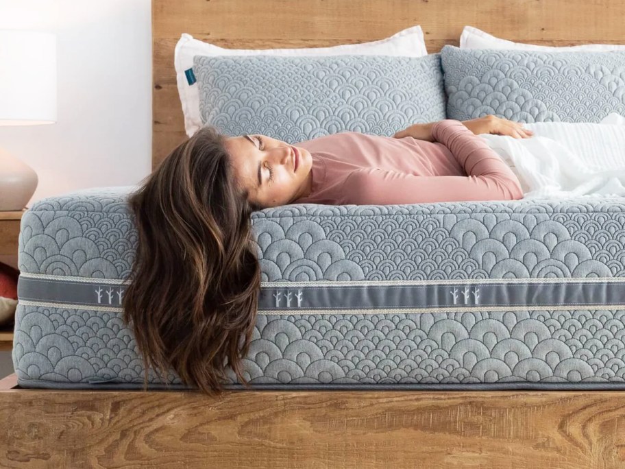 woman laying on a grey mattress on a wood bed frame