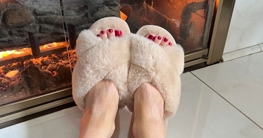 woman wearing Cozyfurry Women's Cross Band Slippers in front of fireplace