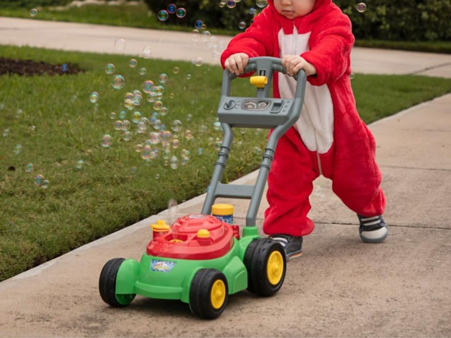 A child dressed like a dinosaur with a Deluxe Bubble Lawn Mower