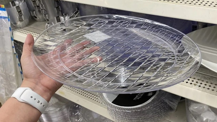 Hand holding a clear circle plastic tray in store