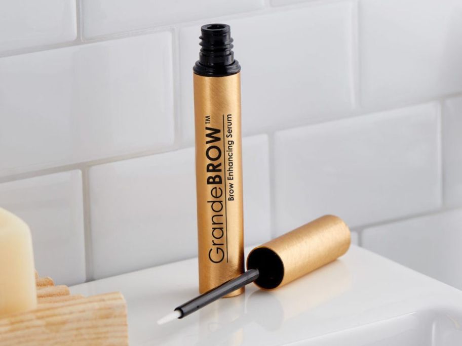 An open tube of GrandeBrow Serum with the wand set next to it