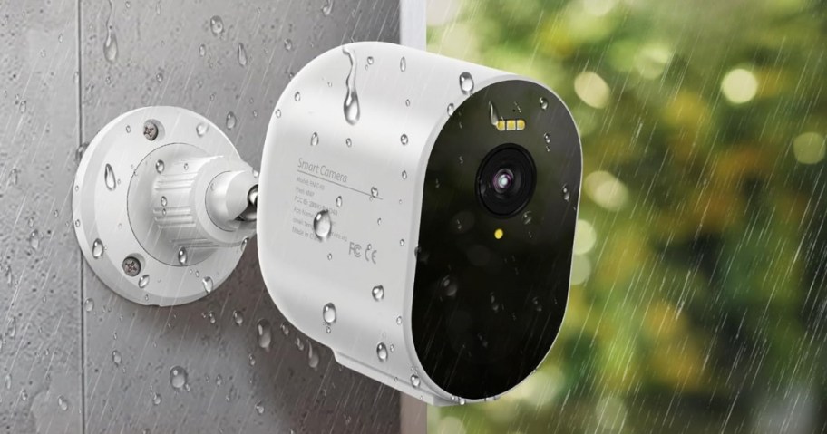 white TENVIS brand Security Camera attached to an exterior wall with rain onlineing down around it