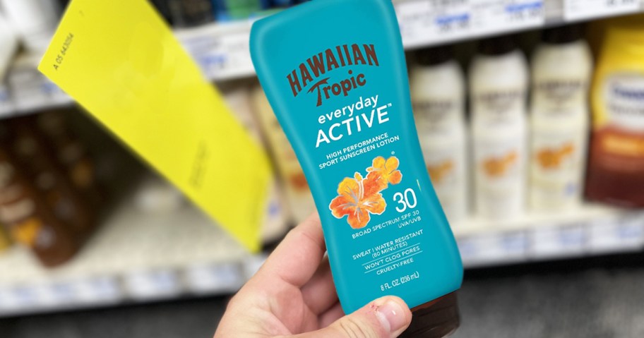 hand holding up a blue bottle of Hawaiian Tropic Sunscreen in store