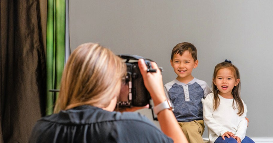 woman with a camera taking a picture of two children